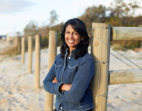 Woman standing in front of a fence on the beach